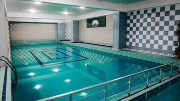 Une piscine dont le fond est recouvert de carreaux à motifs, dotée d’une rambarde de sécurité et ornée d’un logo sur le mur.