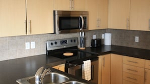 Una cocina moderna con electrodomésticos de acero inoxidable, armarios de madera y encimera negra.