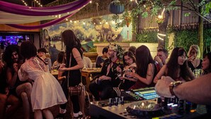 A crowded indoor event with a DJ booth and a mural on the wall.