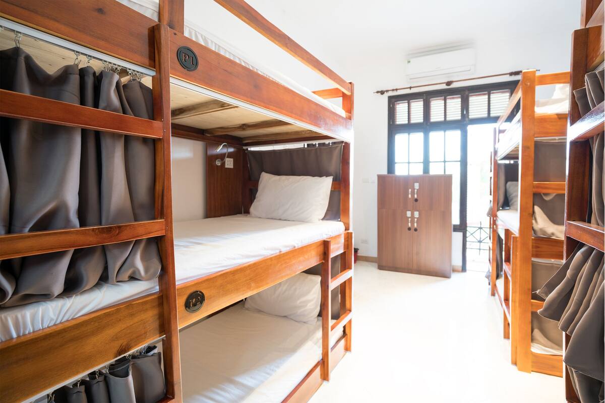 Habitación con literas de madera, un armario y vistas al exterior.