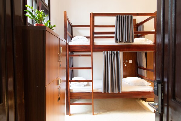 A bunk bed room with a wooden cabinet and a potted plant.