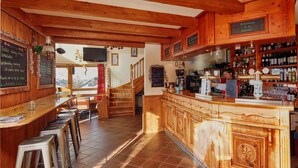 Un espace bar accueillant, avec une décoration en bois, un comptoir avec des tabourets et une vue sur les montagnes.
