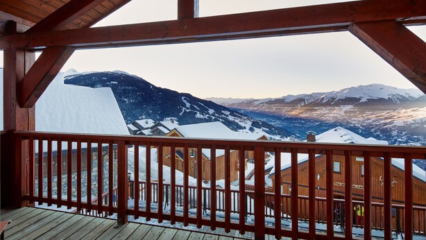 Un balcon en bois offrant une vue sur des montagnes enneigées et un bâtiment en bois portant l’inscription « The Hotel Lad ».