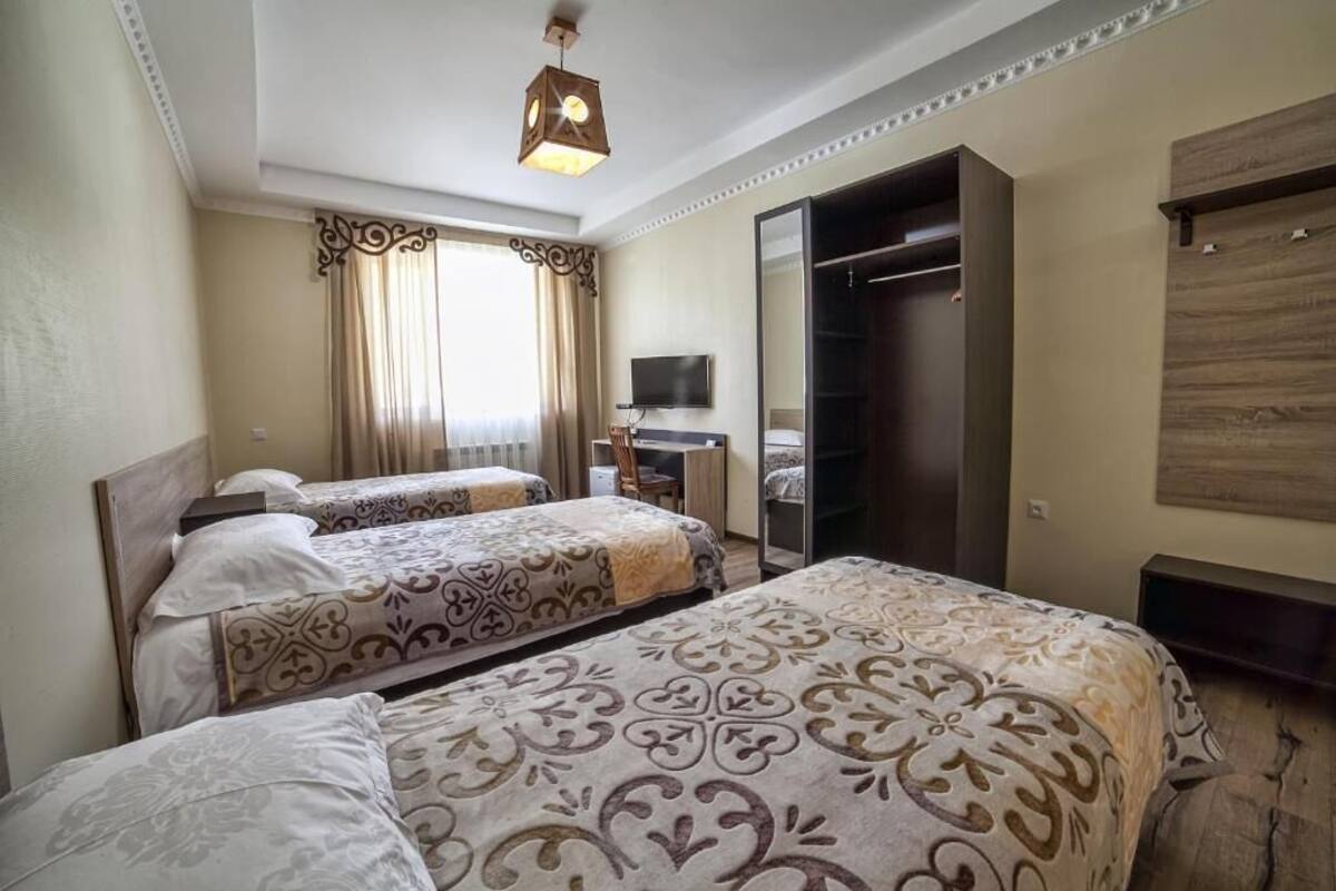 A hotel room with two beds, a desk, a TV, and a wardrobe.