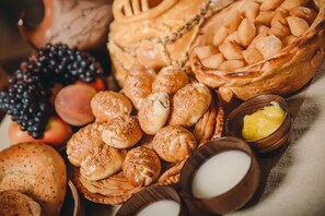 A variety of baked goods including bread, rolls, and pastries, along with some fruits and small bowls containing spreads. - Ethno Hotel Osh (Osh)