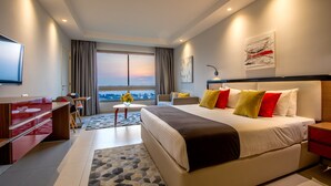 Ein modernes Hotelzimmer mit einem großen Bett, einem Schreibtisch, einem Fernseher und Blick auf die Stadt.