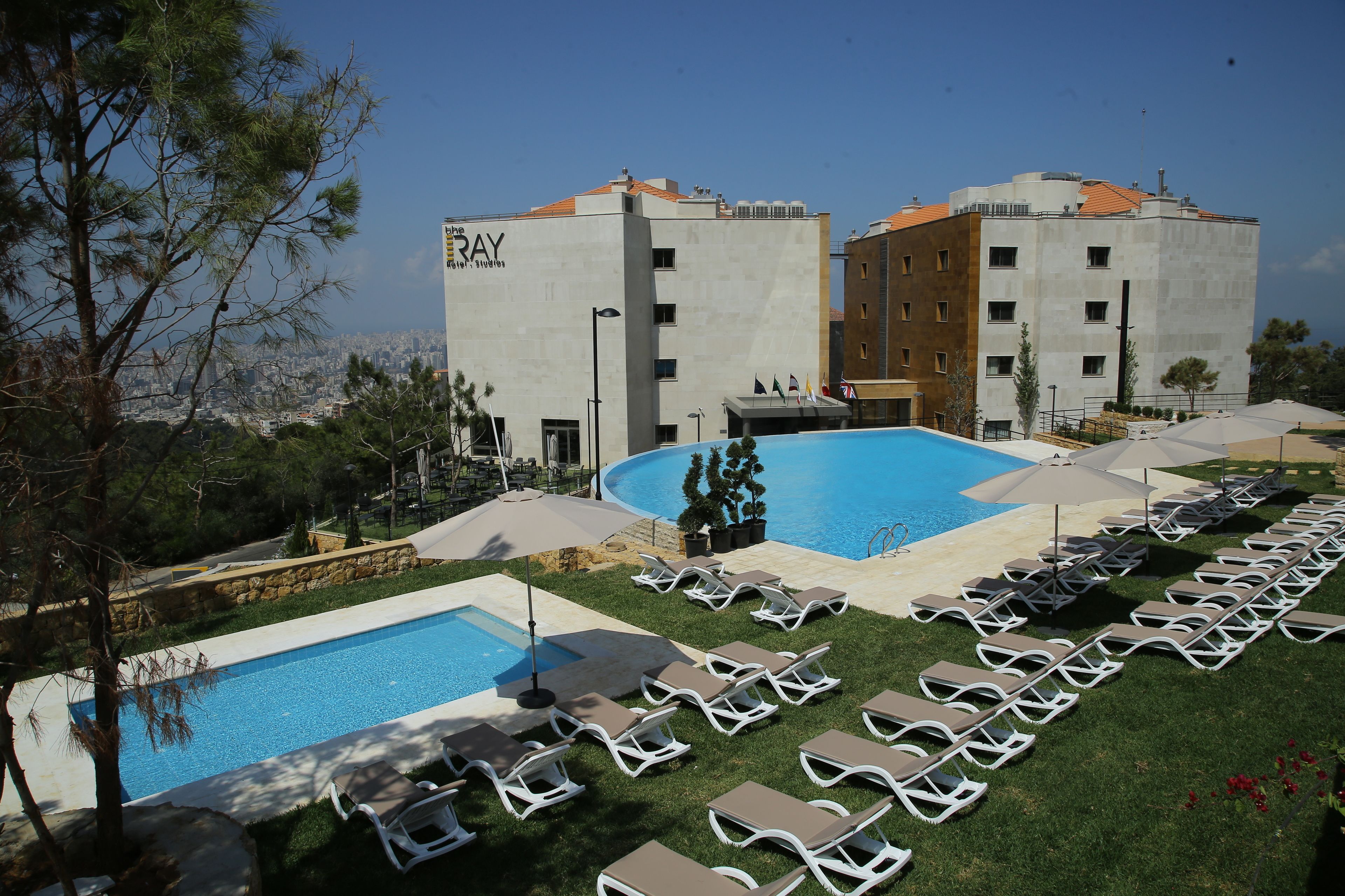 A hotel with a swimming pool, lounge chairs, and a view of the city.