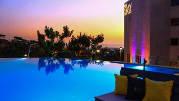 Una piscina al aire libre, sombrillas, sillones reclinables de piscina