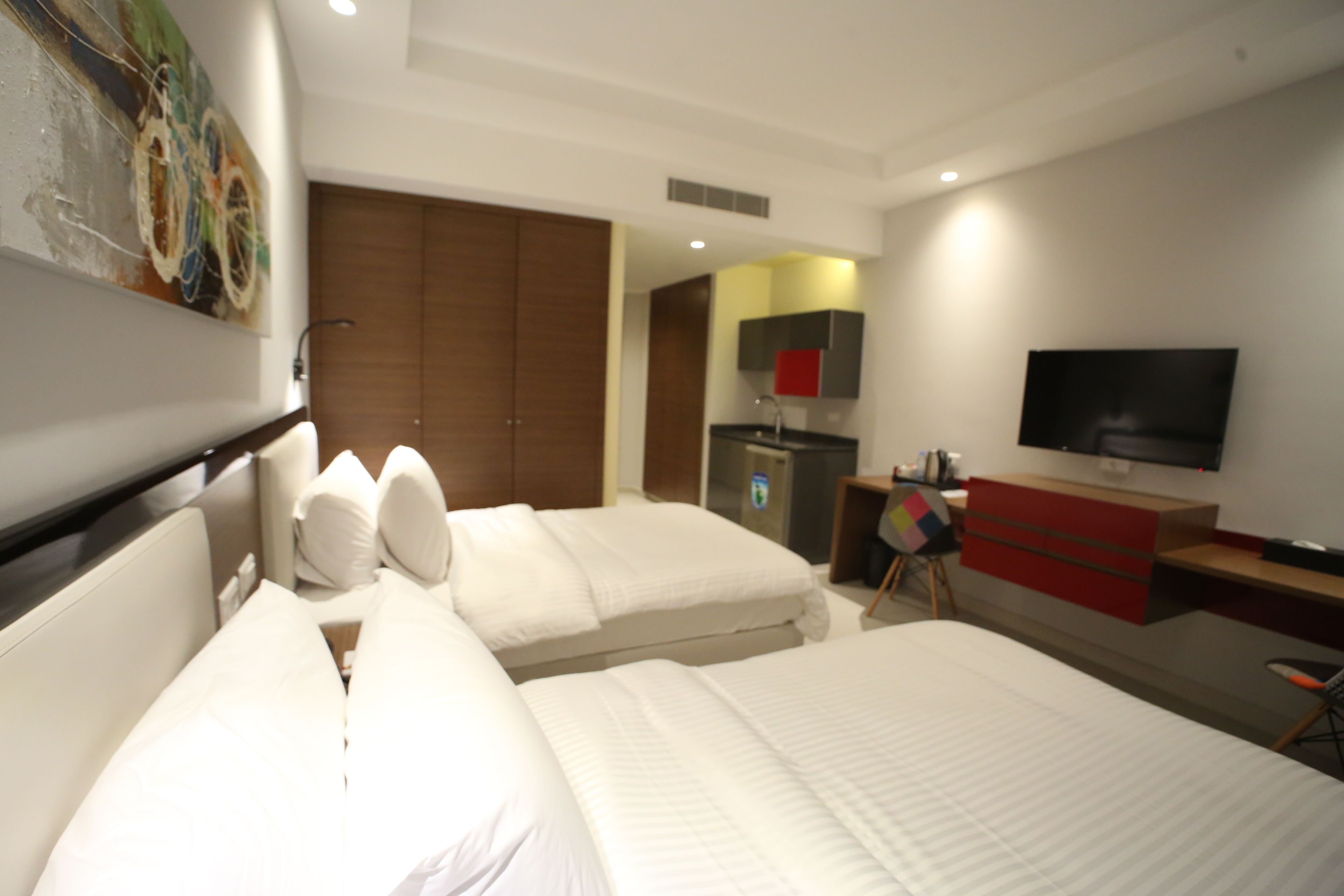 Habitación de hotel con dos camas, televisión, escritorio y armario.