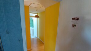 A hallway with yellow walls, a white door, and a wooden floor. - Chambres d'hôtes Les Salles (Beauvoir)