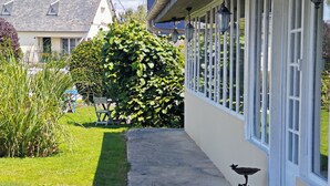 A pathway leading to a building with a large windowed porch, a hedge, and a bird feeder. - Chambres d'hôtes Les Salles (Beauvoir)