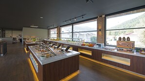 A buffet area with multiple food stations, a brick accent wall, and large windows offering a view of the outdoors.