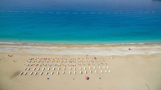 A beach with rows of sun loungers and umbrellas.