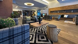 Un vestíbulo amplio con muebles modernos, una mesa de centro de madera y una alfombra estampada.