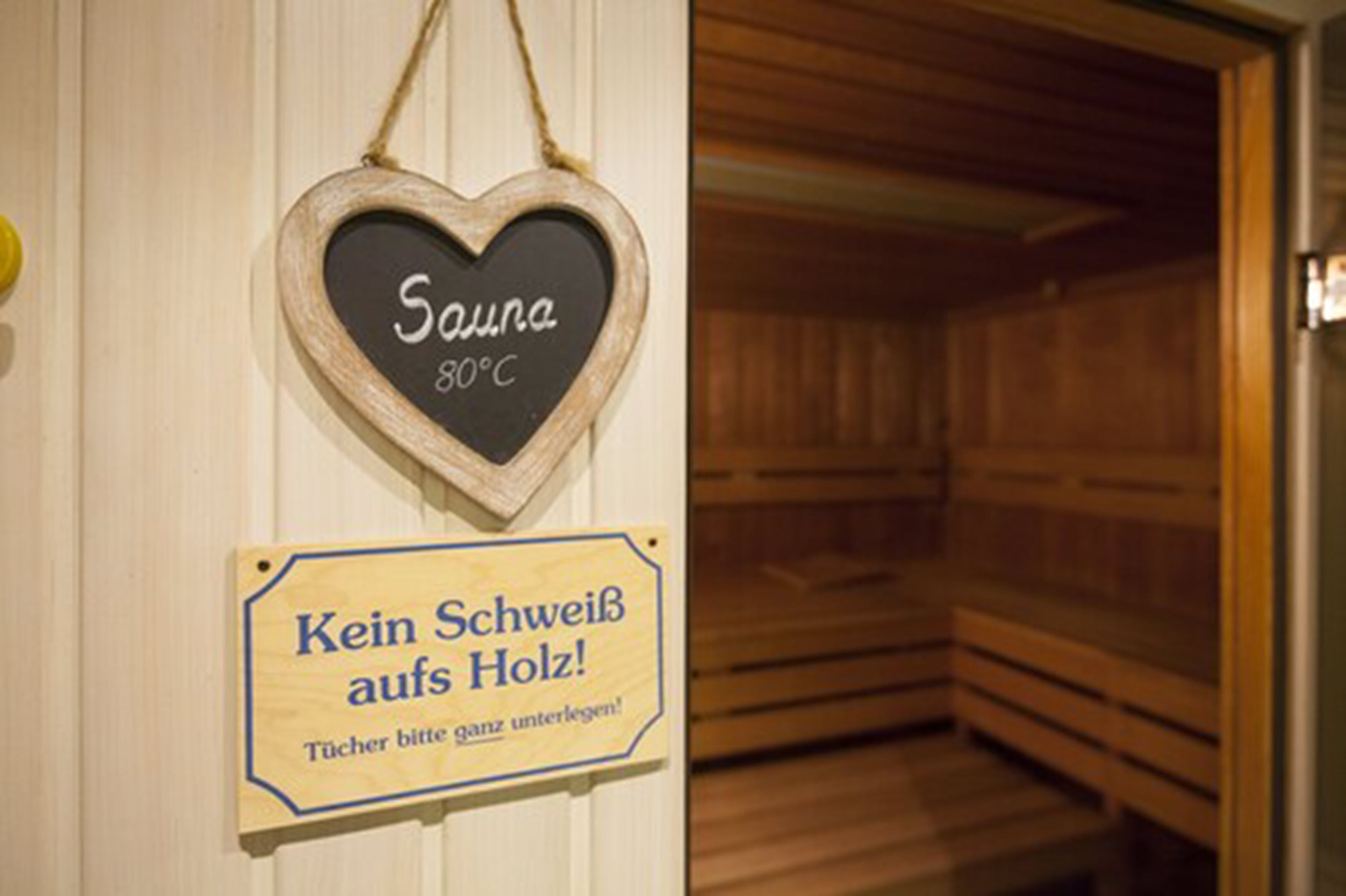 Señal de sauna que indica 'Sauna 80°C' y un banco de madera en su interior.