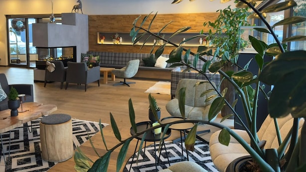 Una sala de estar moderna con chimenea, asientos cómodos y numerosas plantas de interior.