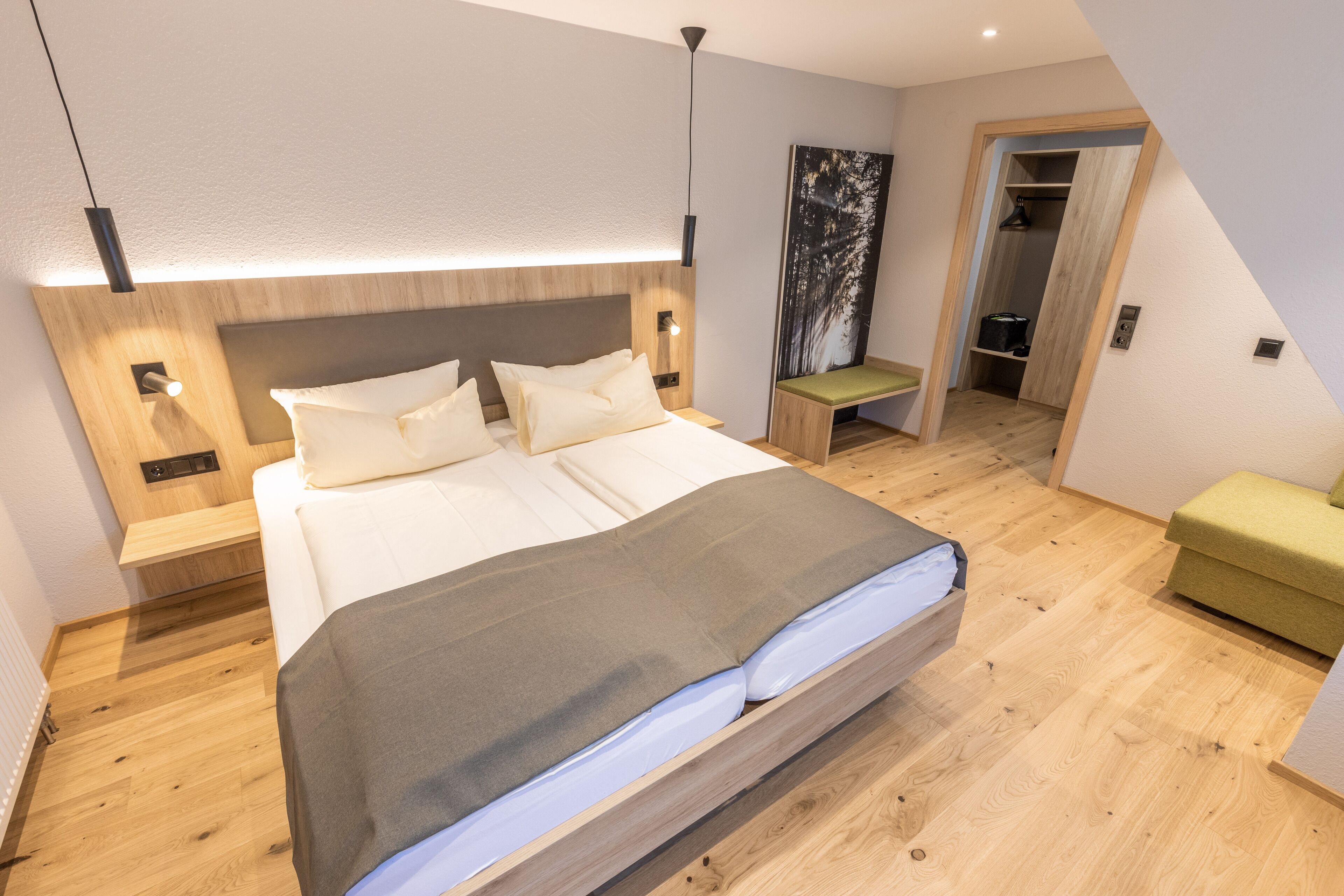 A modern bedroom with a large bed, bedside tables, a bench, and a view of a closet.