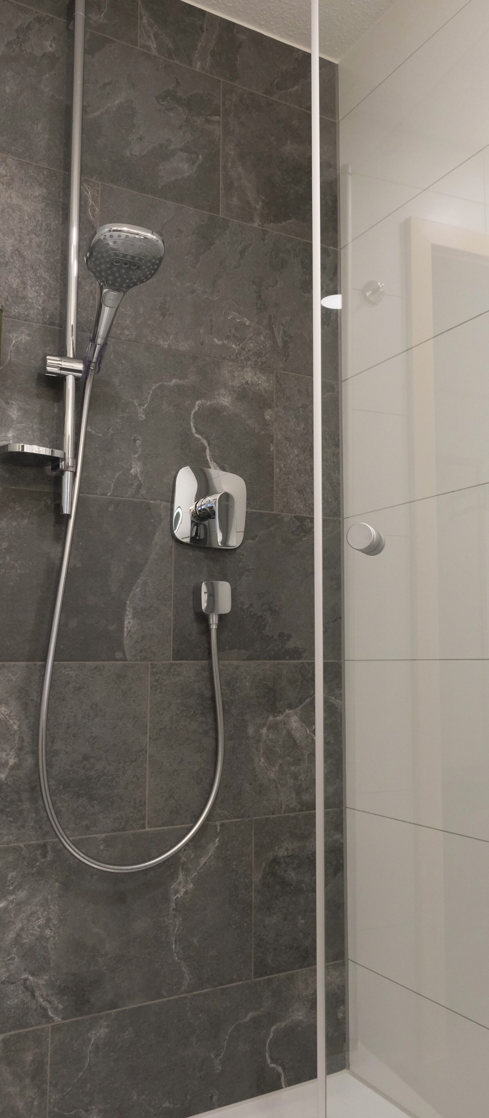 Eine Dusche mit Handbrause und Armaturen an der Wand.
