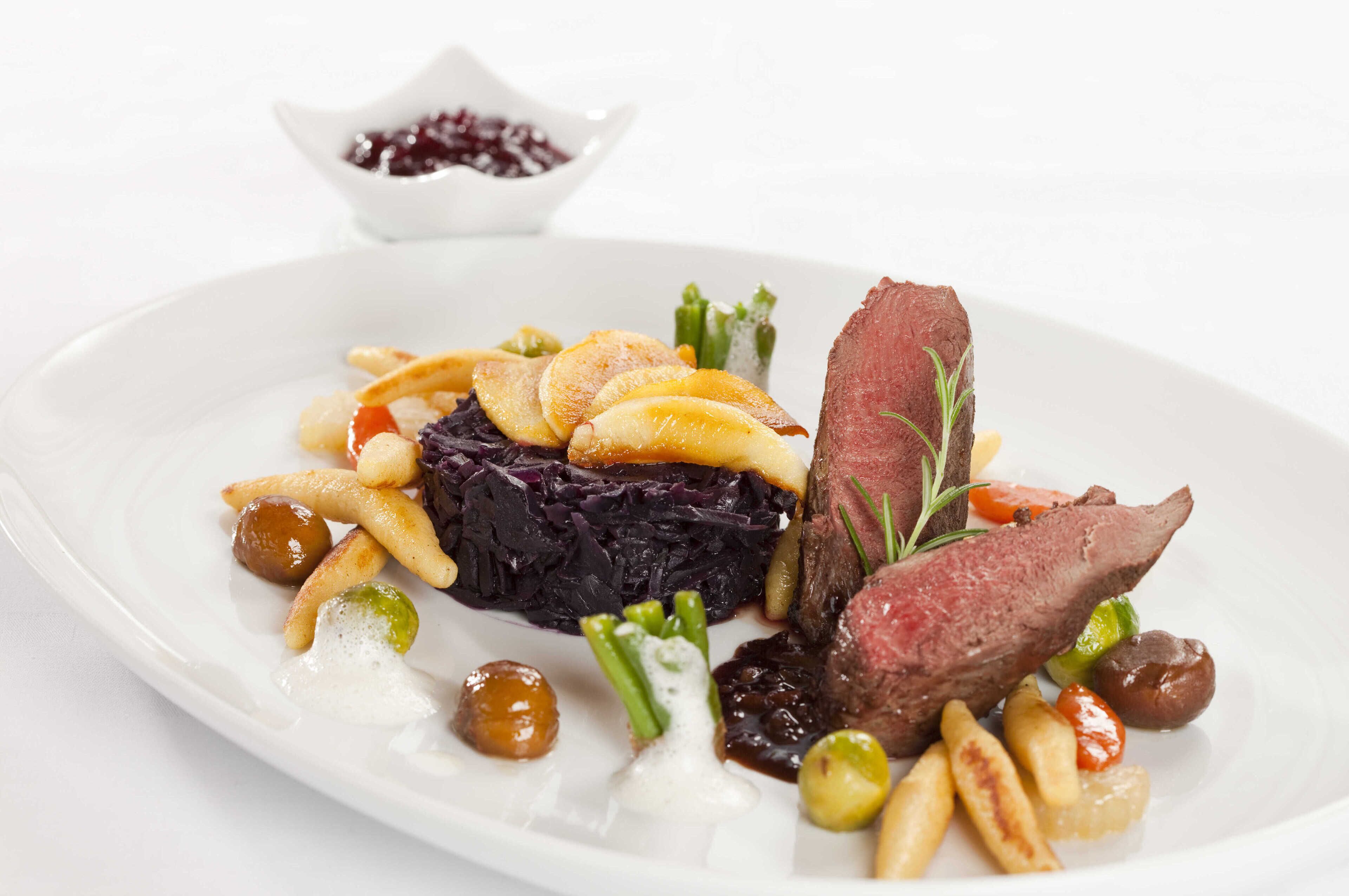 Un plato de comida con filete, col roja y diversas verduras.