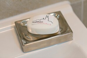 A white hotel room with a metallic object on the sink. - Stadthaus Regensburg (Regensburg)