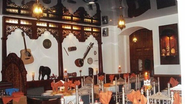 Una habitació amb decoracions murals ornamentades, una guitarra i una taula coberta de espelmes i serretes.