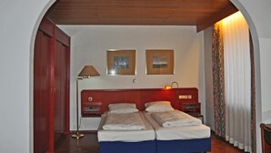 Habitació d'hotel amb un llit doble, dues taules de nit, una làmpada i dos quadres penjats a la paret.