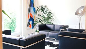 Una sala de estar moderna con un sofá de cuero negro, una mesa de centro redonda y una lámpara de pie.