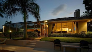 A modern house with a glass facade, outdoor seating, and a well-lit entrance. - House Bethany by Vacationhit (Cape Coral)