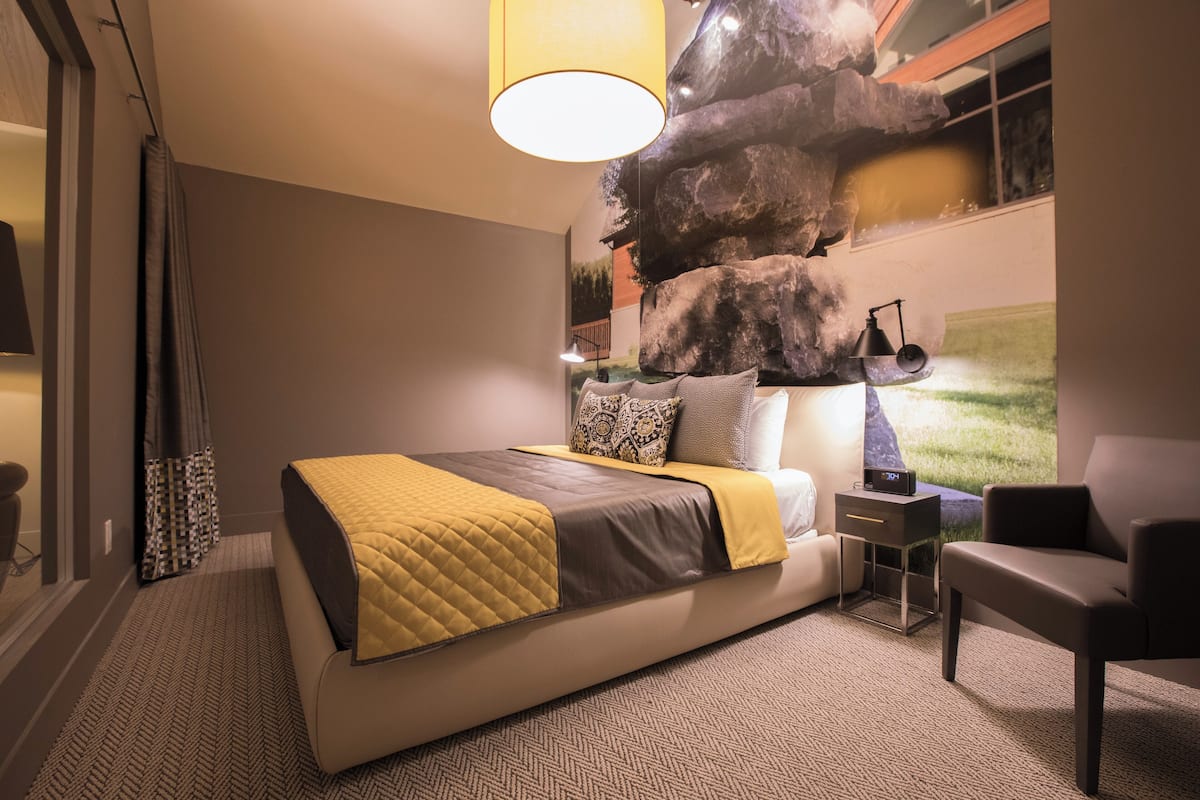 Une chambre moderne avec un grand lit, une table de chevet, une chaise et une fresque murale.