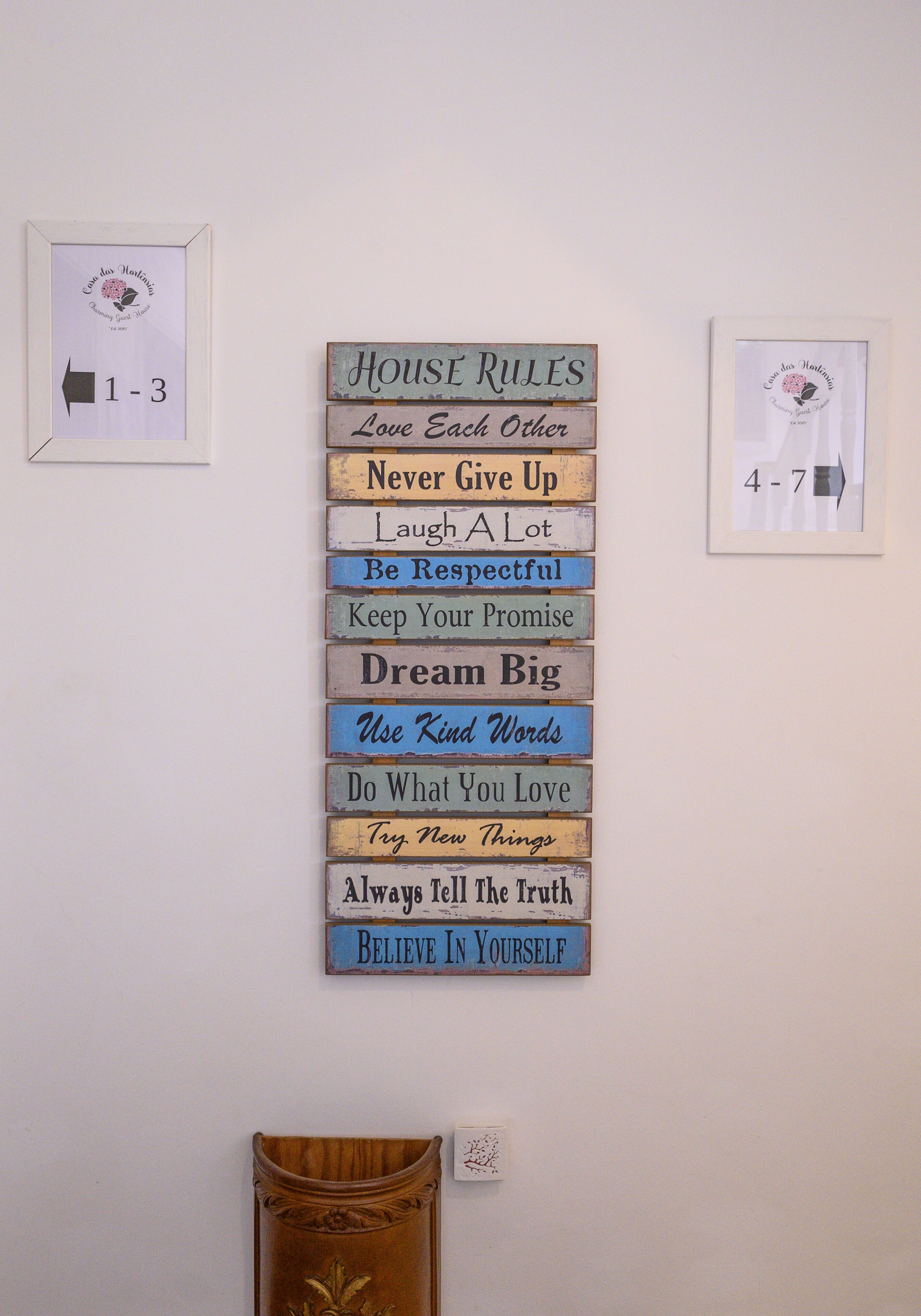 Pared con un cartel que enumera 'Normas de la casa' y frases motivacionales.