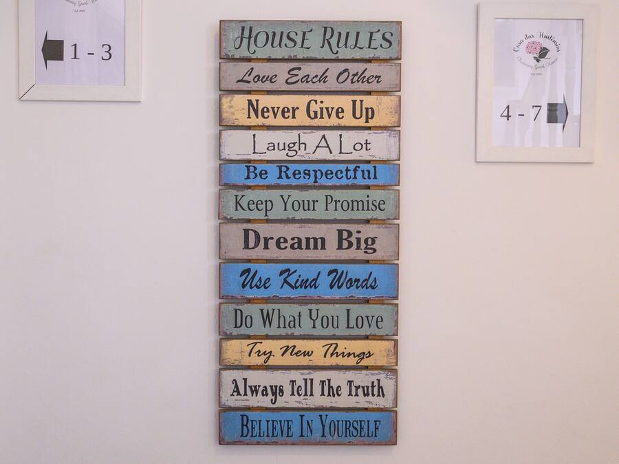 Pared con un cartel que enumera 'Normas de la casa' y frases motivacionales.