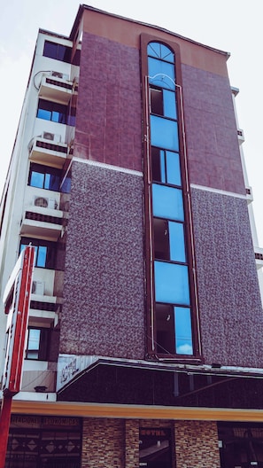 A multi-story hotel with a modern design, featuring a central vertical window and multiple balconies.
