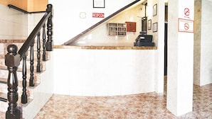 Zona de recepción con mostrador de mármol, una escalera de madera y un letrero que dice 