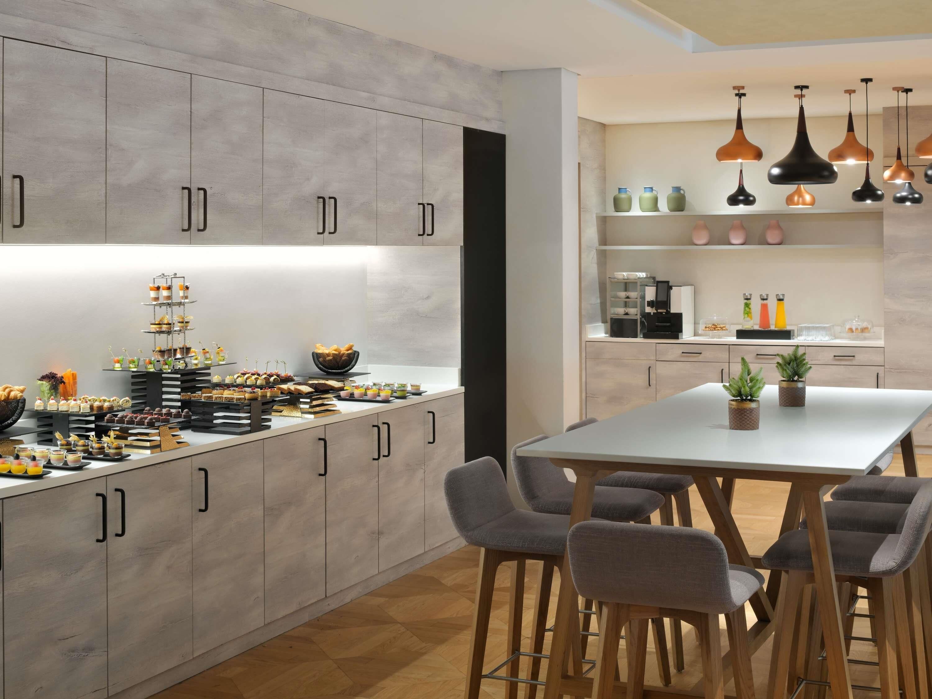 Une cuisine moderne dotée d’un îlot central, de tabourets de bar et de luminaires suspendus.