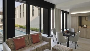 Una sala de estar moderna con sofá, sillas, una mesa de comedor y vista a una piscina.