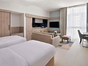 Habitación de hotel con dos camas, kitchenette, televisor y comedor.