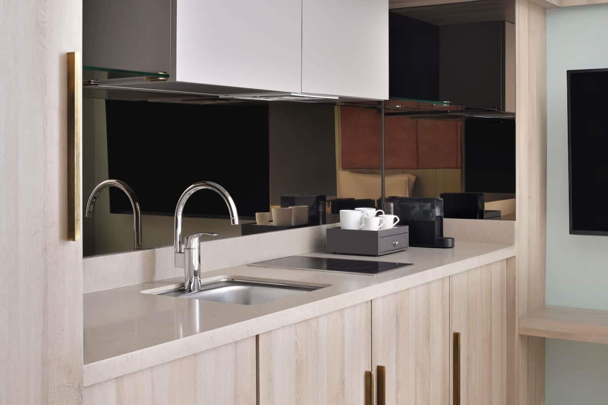 Una cocina moderna con un lavamanos de acero inoxidable, una estufa empotrada y armarios de madera.
