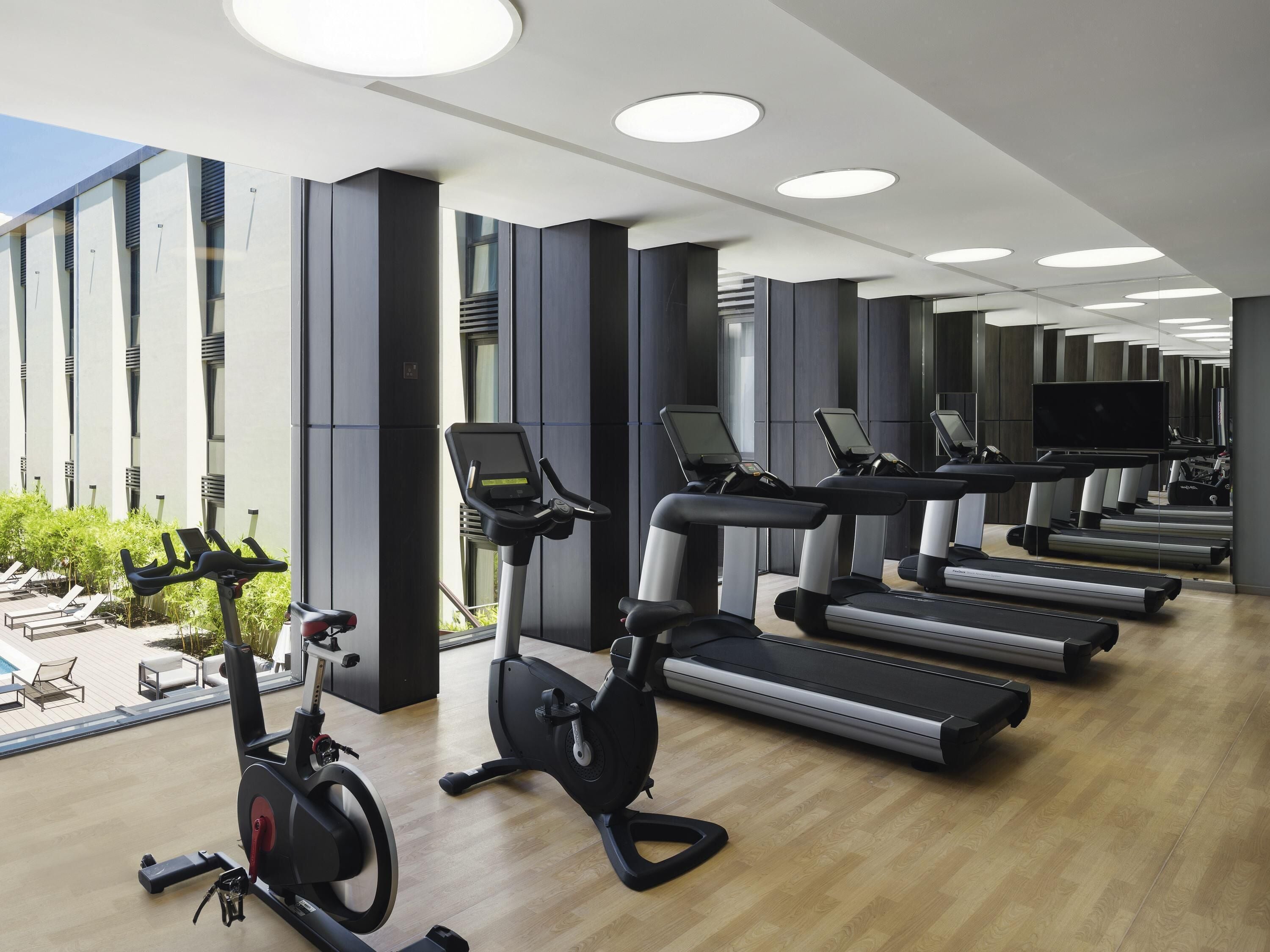 Une salle de sport moderne équipée de plusieurs tapis de course, de vélos d’appartement et d’un rameur.