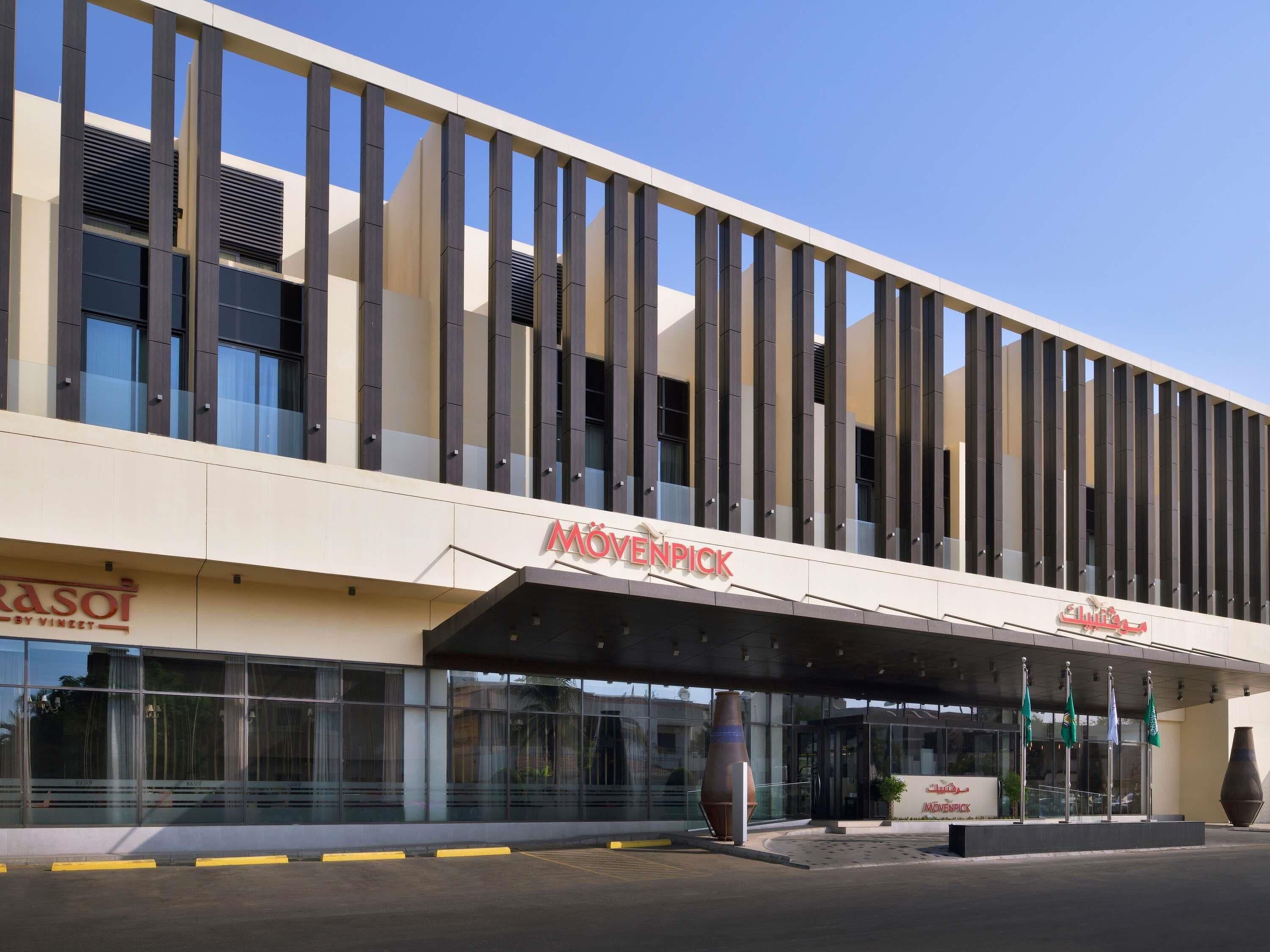 A modern building with a prominent MOVEN PICK sign, large windows, and a covered entrance area.