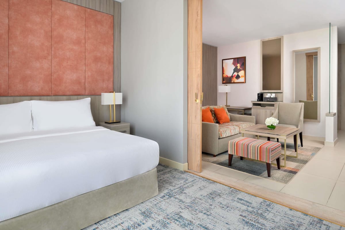 Ett hotellrum med en säng, ett skrivbord, en soffa och en stol.