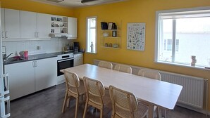 Eine moderne Küche mit weißen Schränken, einem Esstisch mit Korbstühlen und einem großen Fenster, das für natürliches Licht sorgt.