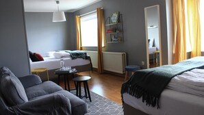 Une chambre moderne avec un lit, un canapé, une petite table et un radiateur.