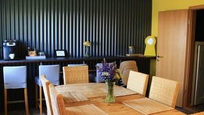 Un coin repas avec une table en bois, des chaises en osier et un vase rempli de fleurs.
