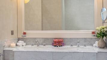 A bathroom with a large mirror, two sinks, and a vase with flowers.