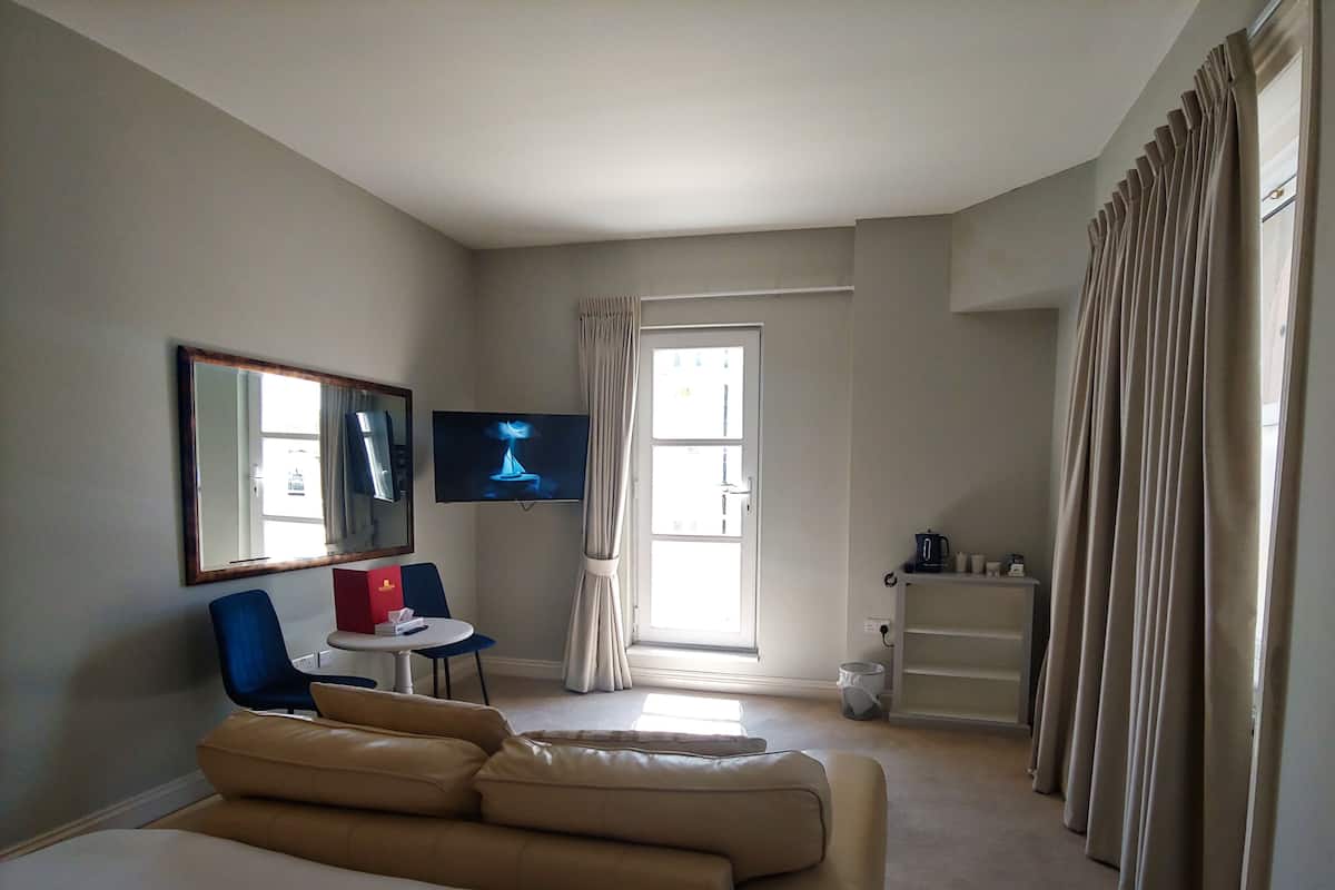 A hotel room with a large bed, a TV, a desk with a chair, and a window with curtains.