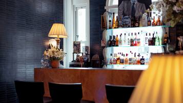 A bar area with a wooden counter, a lamp, and a display of liquor bottles.