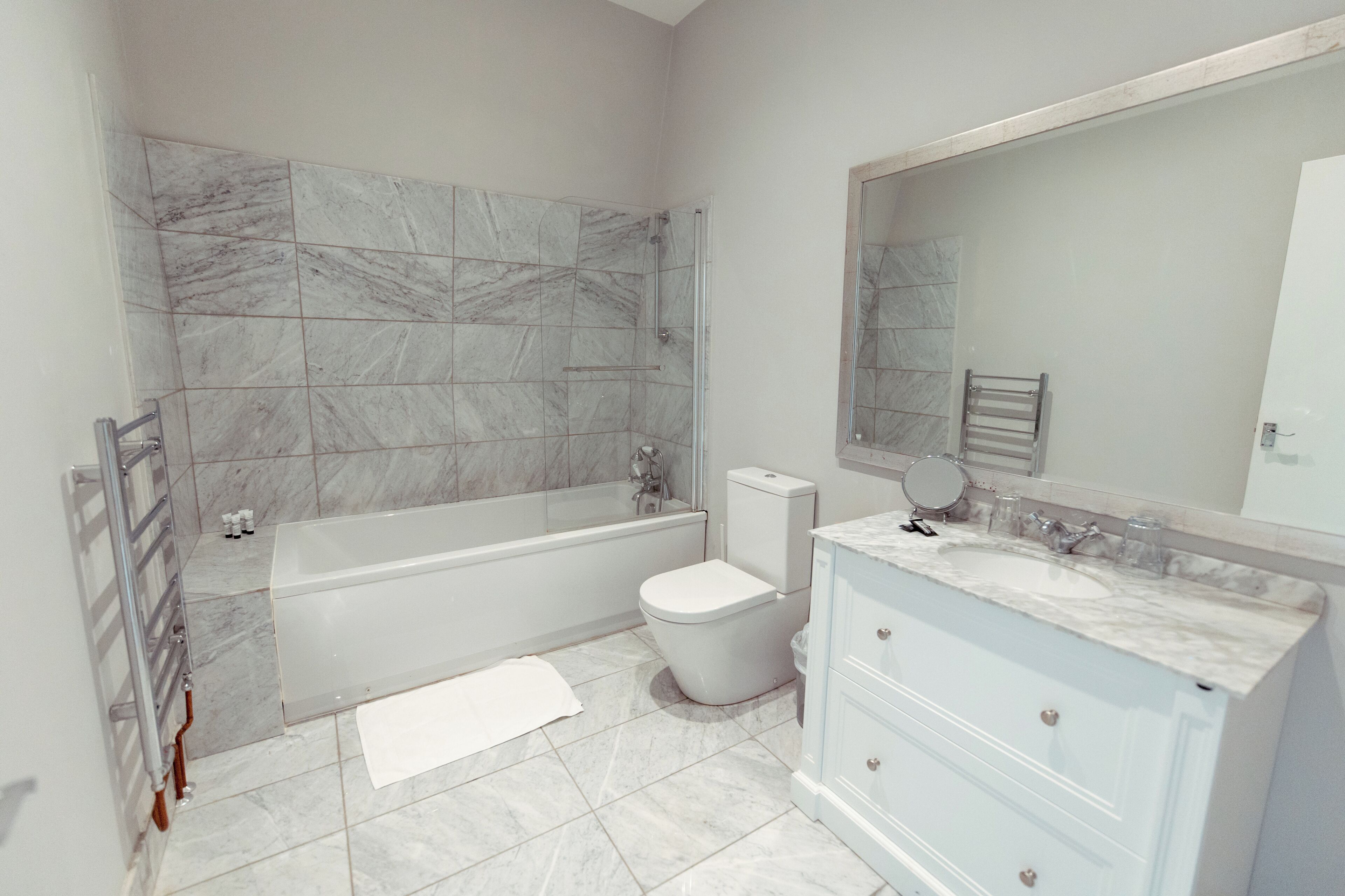 A modern bathroom with a bathtub, toilet, and vanity with a mirror.