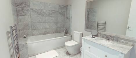 Un baño moderno con bañera, inodoro y tocador con espejo.