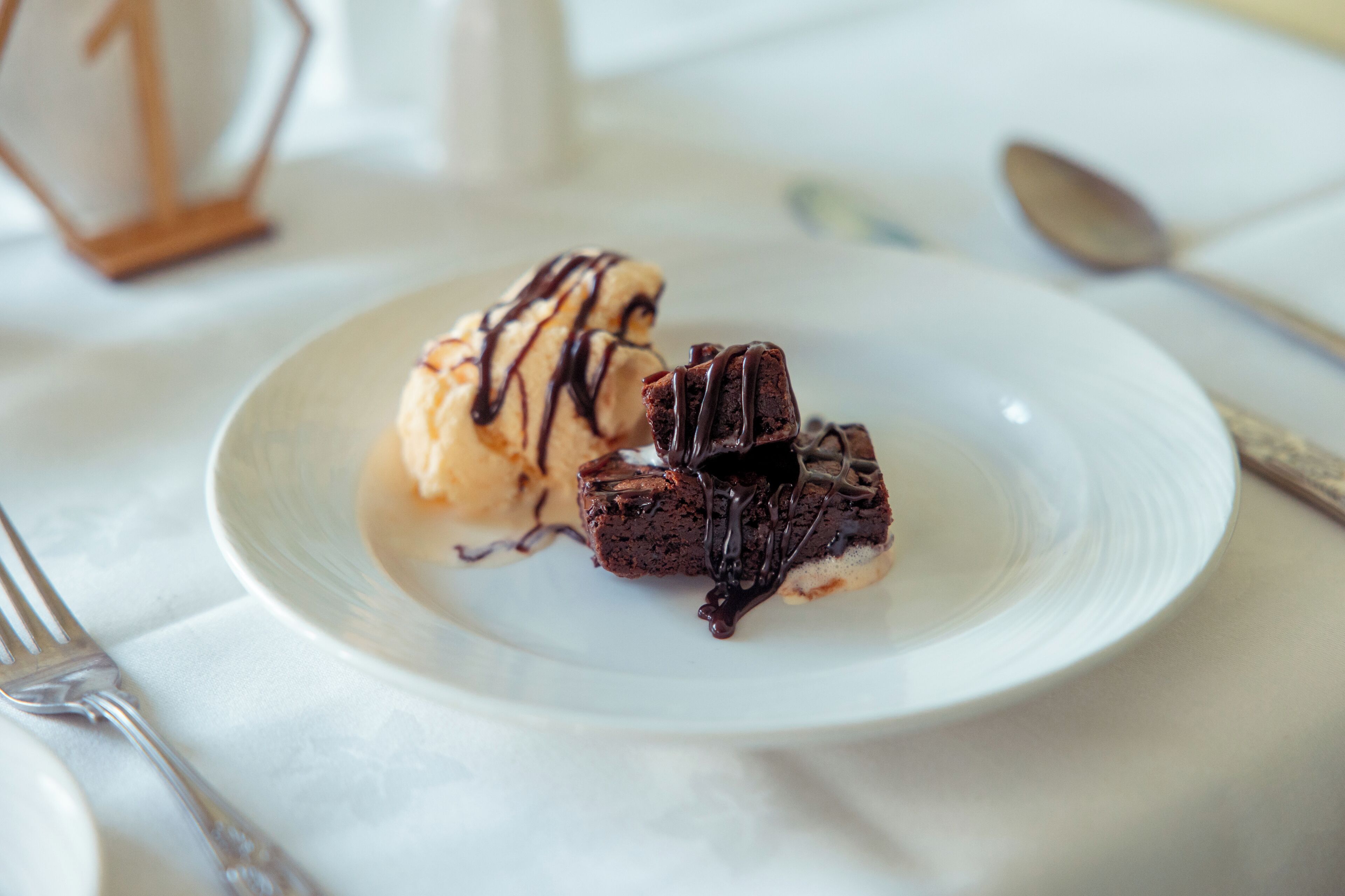 A dessert plate with chocolate cake and ice cream on a white tablecloth.