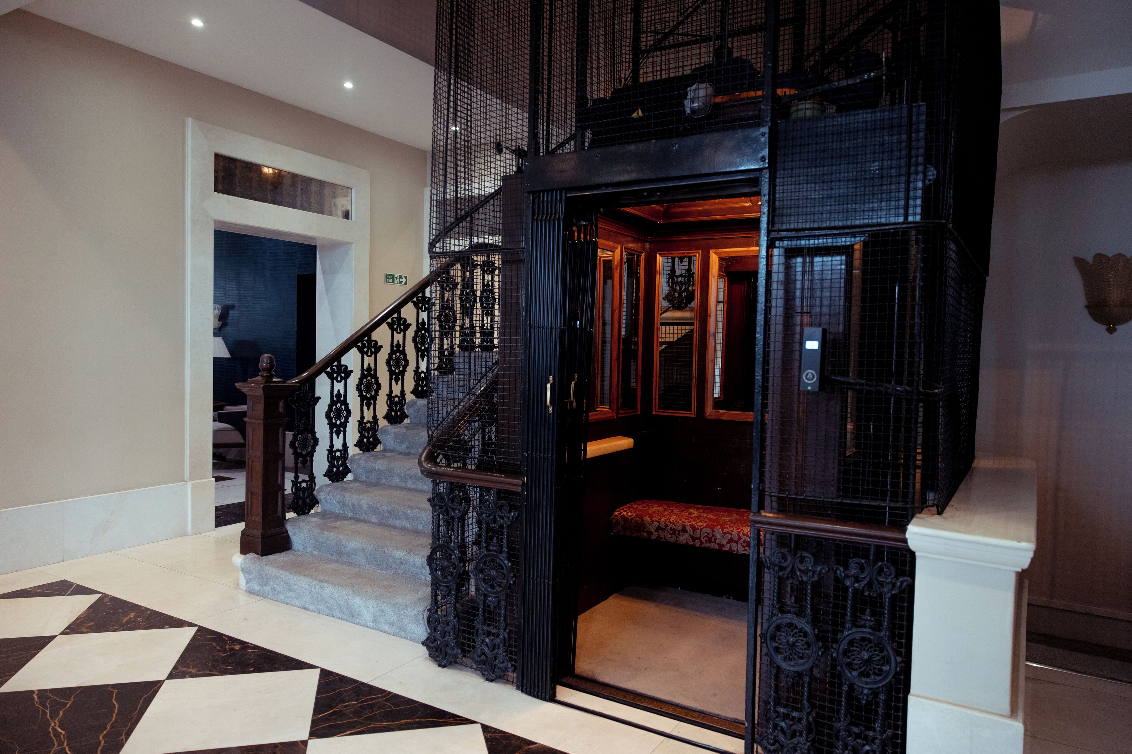 A grand staircase with ornate metal railings and a red cushioned bench.
